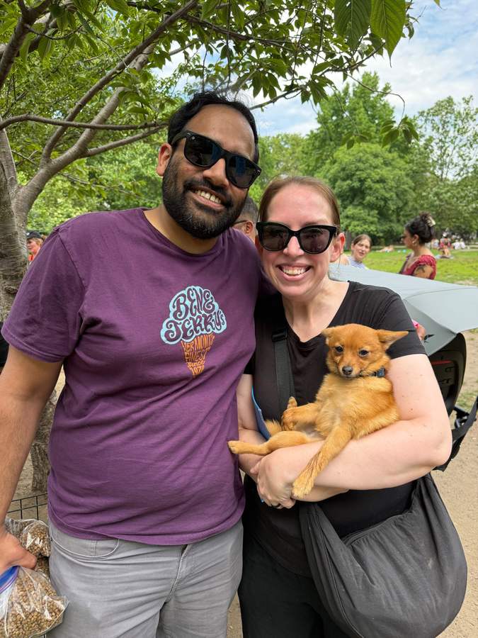 A couple holding a small adopted dog at an adoption event in the park