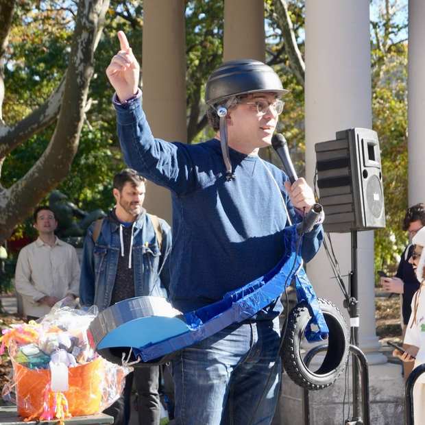 Council Member Lincoln Restler speaking into a microphone in costume at the 2025 McGolrick Halloween Dog Parade